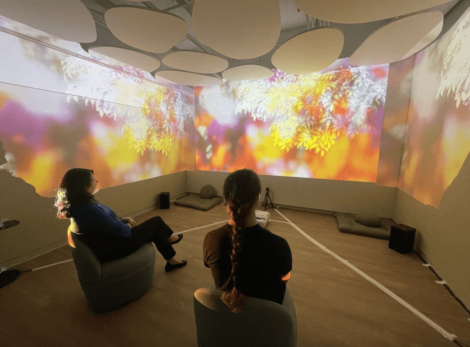 Two people sitting down enjoying the calming projections on the walls in Breakthru’s Wellbeing Room.